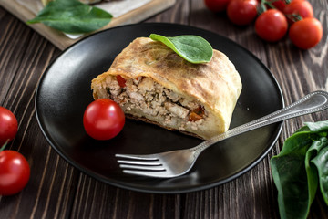 Homemade strudel with meat on a wooden background