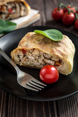 Homemade strudel with meat on a wooden background