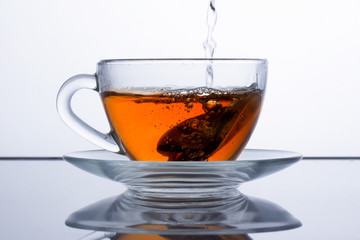 in a transparent cup of tea is poured, black tea is poured