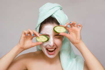 Woman with cucumbers on her eyes and with face cream on her face. Naturotherapy and face skin care concept.