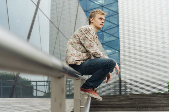 Young man with floral pattern shirt on a cityscape.