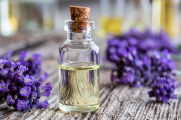 Obraz na płótnie Canvas A bottle of lavender essential oil with fresh lavender flowers