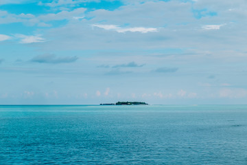 Maldives background. Sunset over the tropical sea and coral beach with colorful clouds in the sky. Boats on the horizon in heavenly atoll of peace and relaxation.