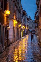 A man with an umbrella on the street. Porec town illuminated by lamps at the evening, Croatia,...