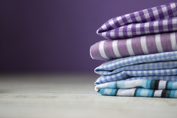 Many kinds of cotton fabrics in stripes and cage on a lilac background. Purple, blue and turquoise fabrics for sewing