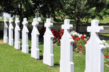 Crosses in cemetery. White gravestones going in perspective.