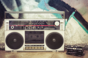 Retro boombox radio with cassettes on a graffiti background / Vintage ghetto blaster with plenty of...