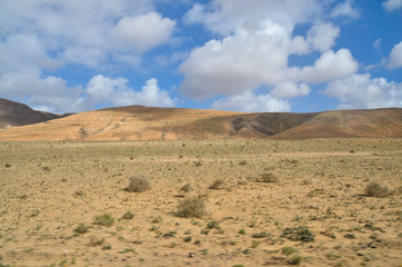 Fototapeta na wymiar cloudy sky over dry desert on lanzarote island