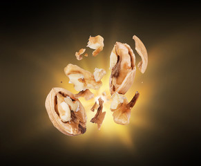 Walnuts crushed into pieces close-up isolated in the dark