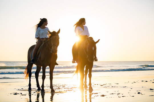 Fototapeta Teens riding horses at the beach