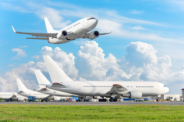 Row of passenger aircraft, airplane parked on service before departure. at the airport, other plane push back tow. One take off from the runway in the sky.