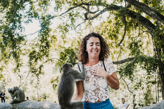 Scared funny woman taking some pictures with a cute monckey in the monckey forest in Ubud, Bali. Lifestyle. Travel photography