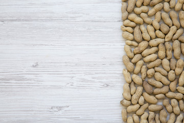 Peanuts in a shell on a white wooden background, top view. Copy space.