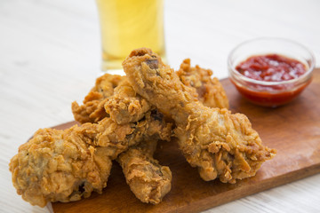 Fried chicken legs with sauce and cold beer, close-up.