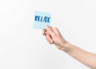 cropped shot of woman holding blue sticky note with Relax lettering, isolated n white