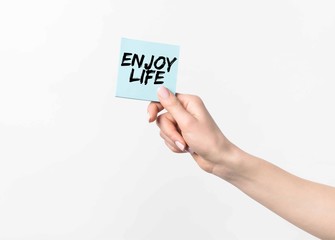 partial shot of woman holding blue sticky note with Enjoy life inspiration, isolated n white