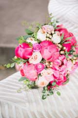 Wedding bouquet with pink and white flowers sitting on white dress