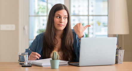 Young student woman studying at home pointing with hand and finger up with happy face smiling