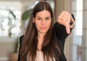 Young beautiful woman at home with angry face, negative sign showing dislike with thumbs down,...