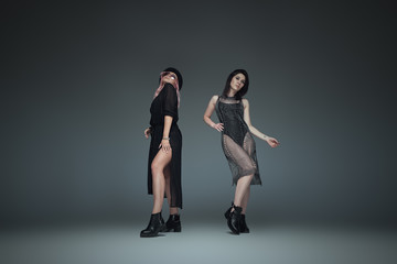 Obraz na płótnie Canvas Two fashionable girls wearing black trendy outfits posing
