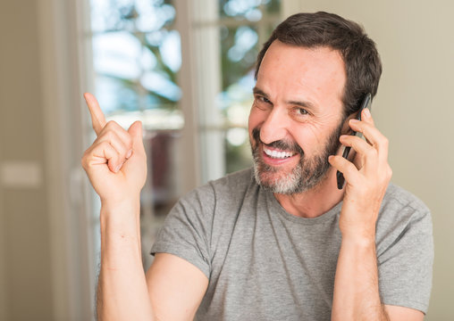 Middle age man using smartphone very happy pointing with hand and finger to the side