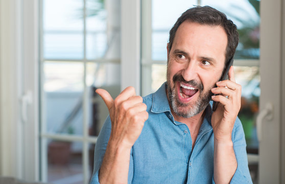 Middle age man using smartphone pointing with hand and finger up with happy face smiling