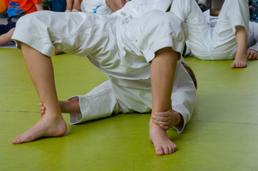 A boy in the kimono practicing karate on the floor in the gym