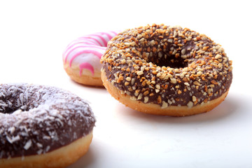 Assorted doughnuts in the glaze, colorful sprinkles and nuts on a white background.