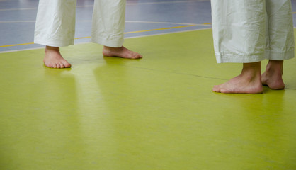 Karate training. Two men are staying straight and waiting for fight. Close-up of two pair of feet. Pattern with place for text 
