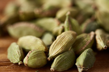 Close-up of green cardamon seeds on rustic wooden background, top view, selective focus, macro.