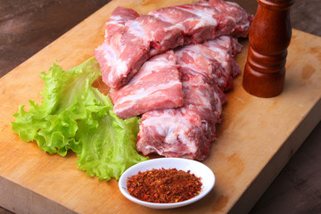 Raw Ribs on a rustic cutting board with salt, pepper and grinder for spices . copy space. Top View.