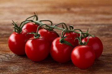 Close-up of a bunch of fresh cherry tomatoes on rustic wooden background, top view, shallow depth of field.