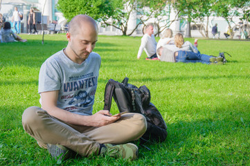 young man on grass with mobile phone, surfing internet