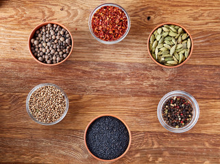 Assortment of spicies arranged in circle on wooden background, top view, close-up, selective focus.