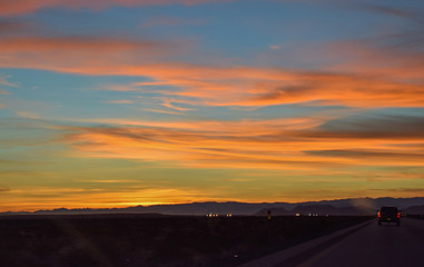 Fototapeta na wymiar Road going right towards sunset. Wispy, glowing clouds