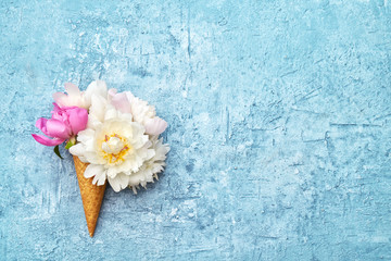 Ice cream cones with white peony flowers on blue background. Summer concept. Copy space, top view