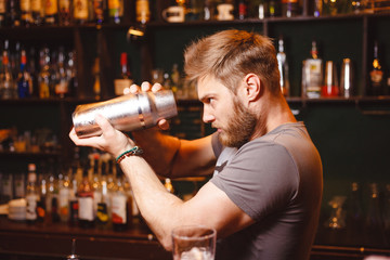 A stern bartender mixes a cocktail in a shaker