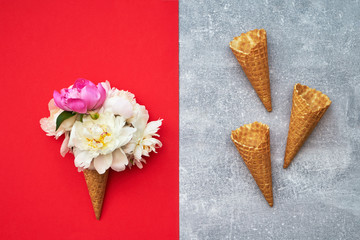 Peonies in a waffle ice cream cone on red background. Copy space, top view, flat lay. Summer concept