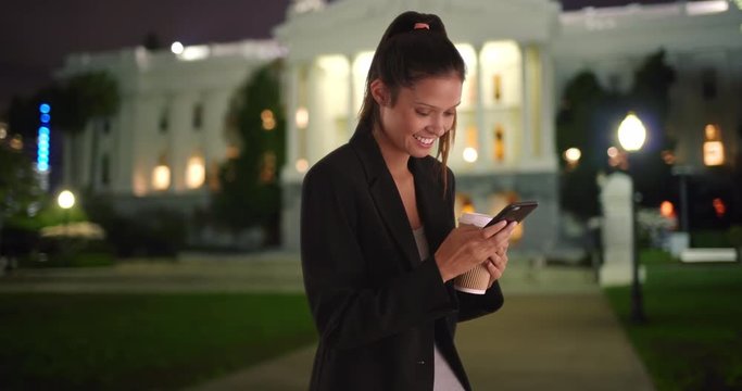 Young female professional or political intern using cell phone at night, Caucasian business woman in black blazer text messaging and smiling, 4k