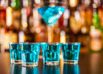 Popular blue drink shot kamikaze on the background of the bar with bottles, a refreshing drink