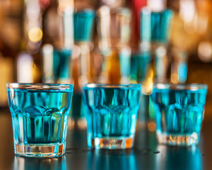 Popular blue drink shot kamikaze on the background of the bar with bottles, a refreshing drink