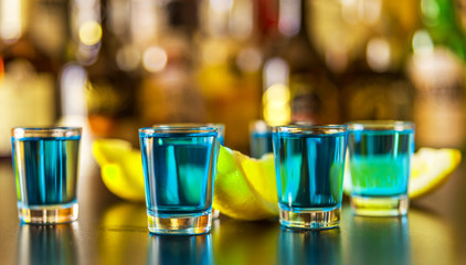 Popular blue drink shot kamikaze on the background of the bar with bottles, a refreshing drink