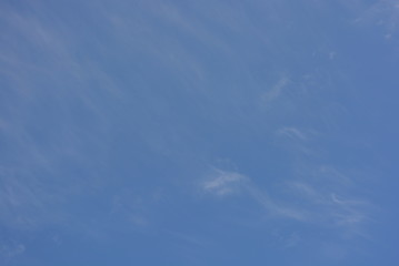 Against the background of a beautiful blue with white translucent tender milk clouds and sunlight