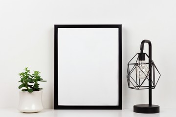 Mock up black frame, succulent plant and industrial style lamp on a shelf or desk. White shelf and...
