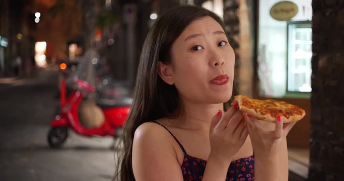Cute millennial female tourist eating pizza in front of restaurant in Florence Italy, Close up of young woman having pizza for dinner in Europe, 4k