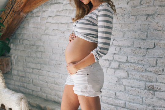 Fototapeta Pregnant woman posing in front of a white brick wall