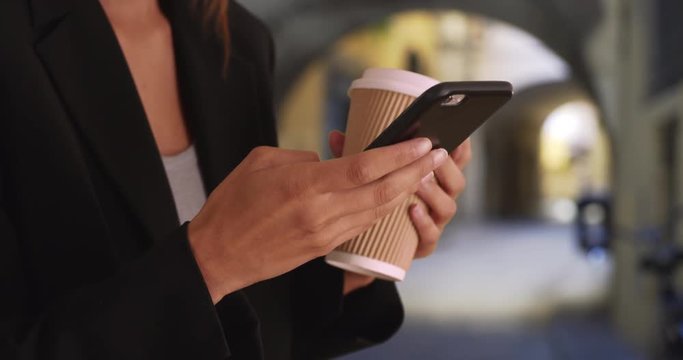 Close up shot of female hands texting on smartphone and drinking coffee on the street on Florence, Tight shot of woman using mobile device and holding to go cup, 4k
