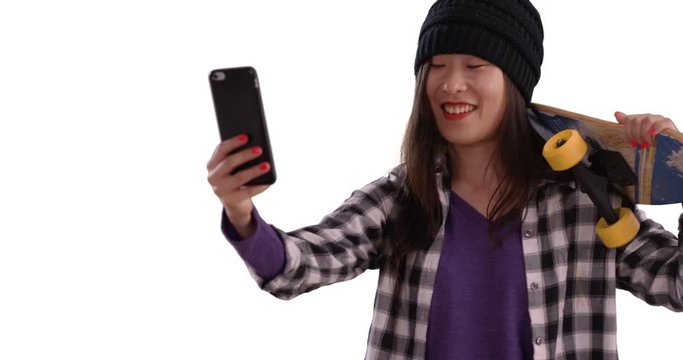 Happy hip millennial woman taking selfie with tech phone camera for copy space, Close view of young Asian woman holding skateboard isolated on white background, 4k