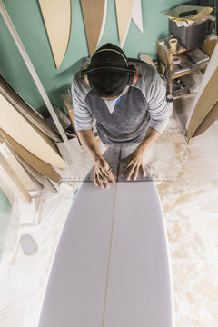Male shaper measuring surfboard tale