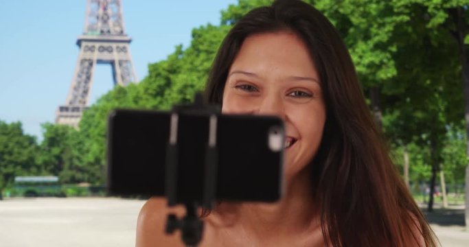 Close up of woman tourist sightseeing in Paris, France using selfie stick, Brunette female on summer travel taking phone selfie near the Eiffel Tower, 4k
